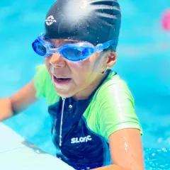 The focus and determination of a young swimmer, equipped with goggles and cap, ready to give her all in the water.
