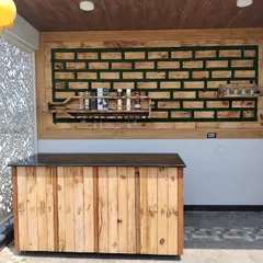The full context of the outdoor bar area I designed. The custom wooden counter and wall art are complemented by the natural light and decorative privacy screen, making it a complete entertainment space.