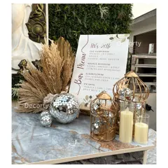 Every detail counts, including a custom bar menu. This menu, designed for the 'RV's 26th' party, is displayed with disco balls, pampas grass, and candles, tying it into the overall event theme.