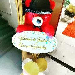 How about a cute and unique welcome for a first birthday? This welcome sign is held by a festive red teddy bear, creating a charming entrance for the little one's party.