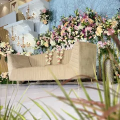 A side angle of a grand reception stage, showing the depth created by layered backdrops and abundant floral arrangements.