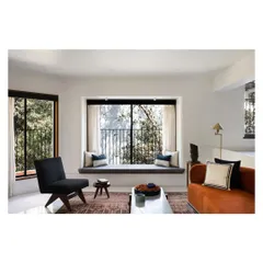 A wider view of the split-level layout, showing how the lower living area with its warm orange sofa relates to the upper dining level. Bay windows on both levels ensure the entire space is filled with natural light.