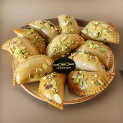 A festive platter of our special Baked Gujiyas. Instead of frying, we bake them to golden perfection and garnish with pistachios, offering a lighter but equally delicious version of the Holi classic.