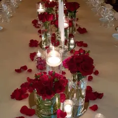 A classic romantic dinner table setup. I used tall glass vases with red roses, floating candles, and scattered petals on a mirrored base to create this timeless and elegant look.