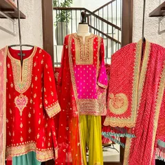 A vibrant display of festive suits in bright reds and yellows. The mix of bandhani dupattas and embroidered kurtas showcases the variety of traditional crafts available in my collection.