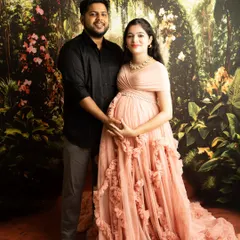 This portrait against a lush, garden-themed backdrop shows how we can create a fairytale feel. The focus is on the couple's shared moment, holding the baby bump together.