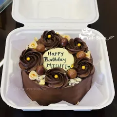 A rich chocolate bento cake for Mishti's birthday. It's decorated with chocolate rosettes, crunchy hazelnuts, and gold leaf for an elegant touch, perfect for an intimate celebration.