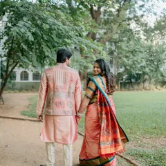 A "follow me" style shot of a couple in traditional wear walking away, with the bride-to-be looking back over her shoulder with a smile. It’s a beautiful and classic pose for any couple photoshoot.