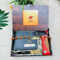 Here is a complete Rakshabandhan gift hamper for a brother. It features a custom wooden box with a photo, containing a personalized wallet, a name-engraved rakhi, a pen, a keychain, and a chocolate bar.