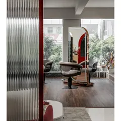 I used fluted glass partitions to create a sense of separation without sacrificing light or openness. This view into the hair styling area shows how the textured glass distorts the reflection, adding an element of artistic abstraction.