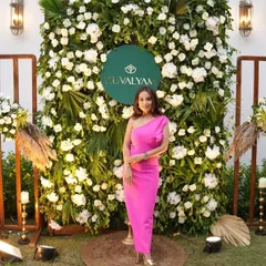 The host posing in front of a stunning floral wall we created for the launch of the brand 'Kuvalyam'. The wall of white flowers and lush greenery with a custom logo was the perfect backdrop for the event.