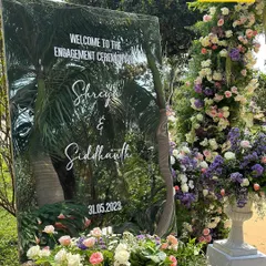 A personalized touch for Shreya and Siddhanth's engagement. A mirrored welcome sign reflects the surrounding greenery, blending modern design with the natural beauty of the garden.