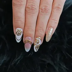An artistic and elegant design featuring a milky white base with intricate, raised gold chrome rose patterns. A gold glitter accent nail completes this luxurious look.