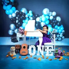 A little musician is turning one. This studio setup features a mini piano and a beautiful blue balloon arrangement, creating a festive and elegant birthday portrait.