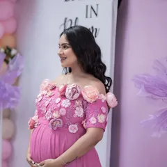 A radiant mother-to-be. This portrait captures her joyful smile and the stunning detail of her floral-adorned pink gown during her baby shower celebration.