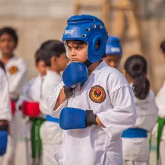 A young competitor, focused and ready for a kumite match. We equip our students, even the youngest ones, with the proper safety gear and the mental fortitude required for competitive sparring.