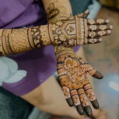This design for a mom-to-be includes a charming baby Ganesha on the palm for blessings. The forearms are decorated with patterns of baby clothes, bottles, and toys.