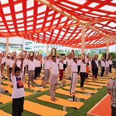 A wide shot of participants at an International Yoga Day event. The collective energy of a large group practicing together creates a powerful and positive atmosphere.