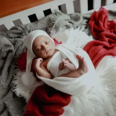 Baby's first Christmas is a memory to treasure forever. This sleepy newborn looks so peaceful and festive, all wrapped up like a little holiday gift.