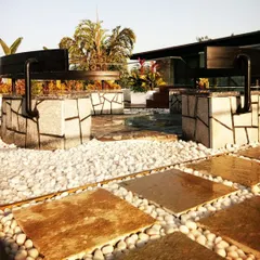 For this terrace, we designed and built custom seating from natural stone with a crazy-paving pattern. The seating is integrated into a landscape of white pebbles and stone pavers, creating a durable and artistic centerpiece.