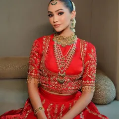 A portrait of bridal elegance. The focus here is on the stunning layered necklace and intricately embroidered blouse, key elements I chose to complement this traditional red lehenga.