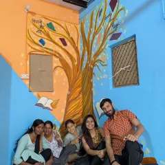 Here we are, the team and I, sitting under the 'Tree of Knowledge' mural we painted at the resource center in Kirari village. The idea was to make learning feel magical, with books growing on trees. It was a joy to bring this concept to life and create a welcoming space for the children.