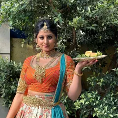 Celebrating Ugadi with a traditional look. The orange and turquoise half-saree is paired with glowing makeup and gold jewelry.