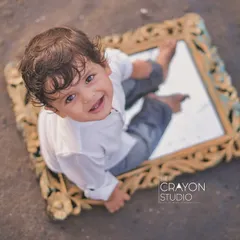 Looking up with a bright, happy smile, this little boy enjoys his unique playtime with a mirror on the sandy shore.