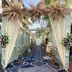 We guide your guests with style. This elegant walkway is lined with tall candelabras and soft drapery, topped with large pampas grass bursts, creating a warm and inviting passage into the main event area.
