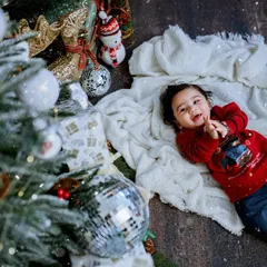 The joy of Christmas morning. This little one is having a wonderful time lying by the tree, surrounded by presents and sparkling lights.