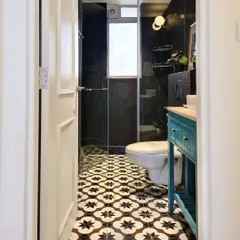After: The moody bathroom in the Breeze Home project. I used dramatic black stacked tiles and a bold patterned floor to create a high-contrast, luxurious feel. The bright blue vanity with slatted details adds a playful pop of color and personality.