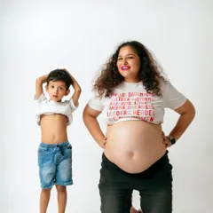 Like mother, like son. This cute pose showing off their bellies is a fun and memorable moment from a family maternity session.
