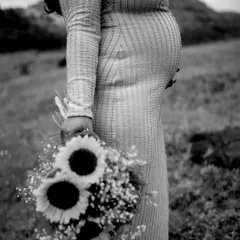 A black and white close-up focusing on the baby bump and the bouquet of sunflowers. It's an artistic and timeless shot that celebrates the beauty of new life.