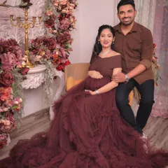 A classic portrait from a maternity session. The couple is seated against our ornate white mantelpiece, which is decorated with a lush arrangement of burgundy and blush flowers, creating a warm and romantic setting.