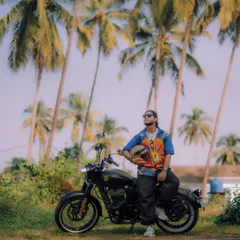 Posing with a black Royal Enfield against a classic Goan backdrop of palm trees. This image showcases the bike's sleek design in a travel context, appealing to riders who love to explore.