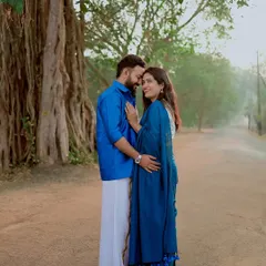 A full-length portrait showing the beautiful coordination of their traditional outfits against the backdrop of a massive banyan tree.