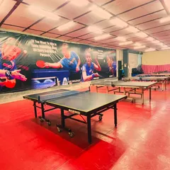 Another angle of our training hall, showcasing the row of tables ready for action. The large mural features table tennis legends, inspiring our players every day.