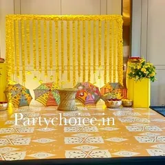 We designed this indoor Haldi setup with a dominant yellow theme. The backdrop is a curtain of marigold strings, complemented by colorful Rajasthani umbrellas and a custom-printed floor mat for a cohesive and cheerful look.
