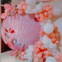 Welcoming a precious little one with this soft and elegant baby shower decor. The round "Welcome Little One" backdrop is framed by a cascade of pink and white balloons, with delicate paper flowers and monstera leaves for a modern, gentle touch.