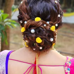 My love for curly textured buns will never fade. This beautiful updo is adorned with small yellow flowers and pearls for a delicate touch.