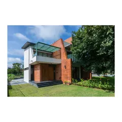 An exterior view of 'An Earthy Affair', a home designed to celebrate natural materials and its connection to the landscape. We used exposed brick and large openings to create a structure that feels rooted and honest. The design plays with solid volumes and open terraces to create a dynamic relationship with the surrounding green space.