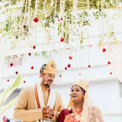 A joyful portrait of the Odia bride and Telugu groom under their floral mandap. Their smiles reflect the happiness of their union, a beautiful blend of two South Indian cultures.