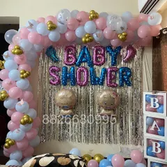 A closer look at the baby shower backdrop, featuring 'BABY SHOWER' foil balloons and cute baby-shaped foils against a shimmering curtain.