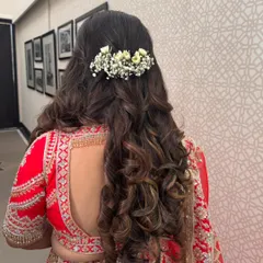 A beautiful half-up style with big, voluminous curls, decorated with a bar of fresh baby's breath. This is a stunning look for a bride on her wedding day.