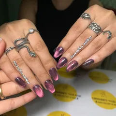 A dramatic and moody look. This set features a deep purple base with a vibrant pink cat eye effect, creating a magical glow that shifts in the light. The accent nails have a subtle glitter finish.
