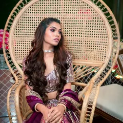 A regal pose in a peacock chair. The makeup is fit for a queen, with a strong eye look and perfectly sculpted features that command attention.