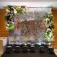 This shimmering silver sequin wall with a custom neon sign is designed to be the ultimate photo backdrop. Framed with white florals and tropical leaves, it adds a touch of modern glamour to any Sangeet or cocktail event.