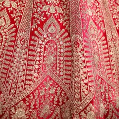 A close-up of the golden threadwork on a red bridal lehenga. This detailed craftsmanship is what makes my custom ethnic wear so special.
