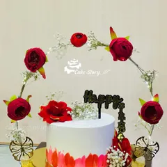 A stunning cake set inside a floral frame. This design features a simple white and red cake surrounded by an arch of red flowers and lights, creating a beautiful centerpiece.