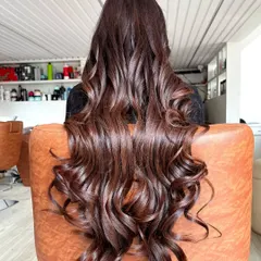 A beautiful final look of a rich chocolate brown color service. The hair is styled in deep, cascading curls to showcase the multi-tonal quality and incredible shine of the new color.